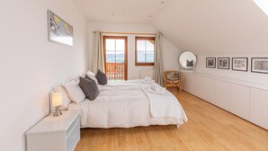 A bedroom with a large bed, a chair, a window with a view, and framed pictures on the wall. - Villa-view, Pool, Bbq, Playground & Fire pit (Horni Plana)