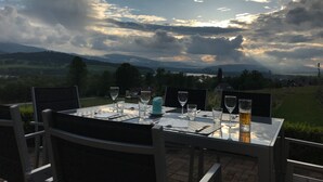 An outdoor dining table set with chairs, overlooking a scenic landscape with hills and a lake. - Villa-view, Pool, Bbq, Playground & Fire pit (Horni Plana)