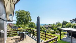 A wooden deck with a table and chairs, overlooking a garden and a body of water. - Amazing home in Allinge with kitchen (Allinge)