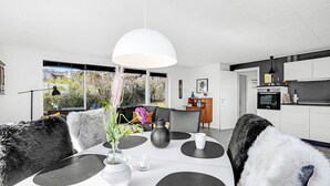 A modern dining area with a white table, black and white chairs, and a white vase with flowers. - Amazing home in Allinge with kitchen (Allinge)