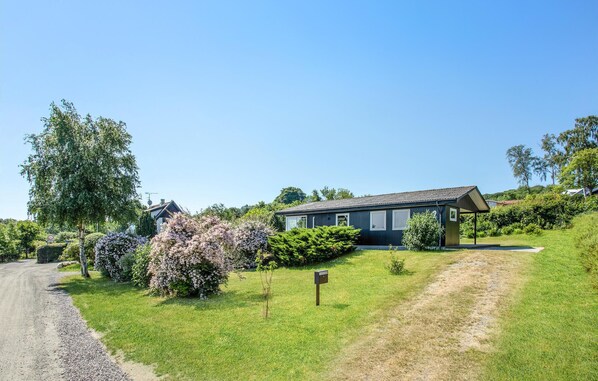 A modern house with a large garden, a gravel driveway, and a mailbox.