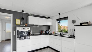 A modern kitchen with white cabinetry, a black countertop, and a window providing a view of the outdoors. - Amazing home in Allinge with kitchen (Allinge)