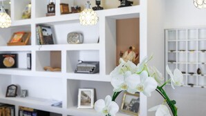 Une pièce avec des étagères blanches où sont rangés divers objets, comme des livres, une machine à écrire et des objets décoratifs.