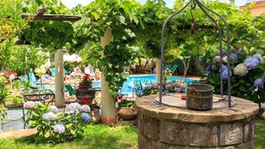 Un jardin avec une piscine, un espace salon extérieur et une pergola couverte de plantes grimpantes.