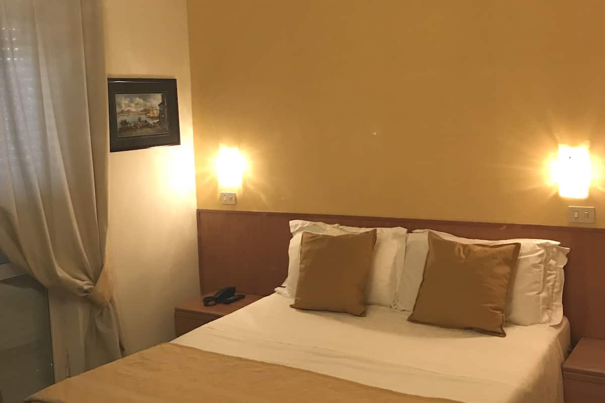 Een hotelkamer met een groot bed, twee bedlampen, een nachtkastje en een foto aan de muur.