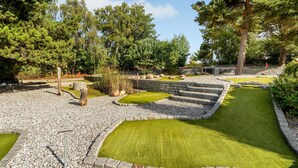 A miniature golf course with stone walls, green grass, and trees.