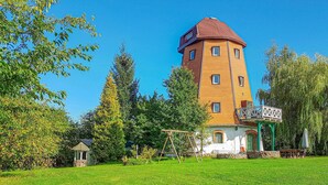 A multi-story building with a distinctive tower, surrounded by lush greenery and a well-maintained lawn. - 3 bedroom amazing home in Sterlawki Male (Sterlawki Male)