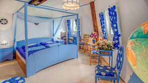 A bedroom with a four-poster bed, a desk with a chair, and a small table with a vase of flowers. - 3 bedroom amazing home in Sterlawki Male (Sterlawki Male)