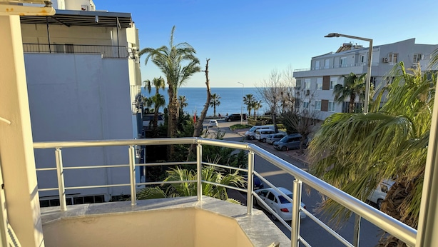 A balcony with a view of the street, palm trees, and a building across the street. - Premier Inn City  (Antalya)