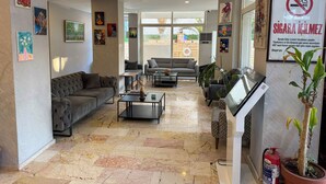 A hotel lobby with a marble floor, multiple sofas, a coffee table, and various artworks on the walls. - Premier Inn City  (Antalya)