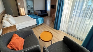 A hotel room with a bed, two armchairs, a small table, a sofa, a TV, and a bathroom visible through an open door. - Premier Inn City  (Antalya)