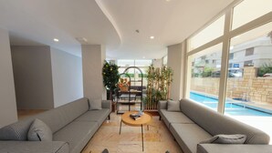A modern living room with two sofas, a coffee table, and a view of a swimming pool. - Premier Inn City  (Antalya)