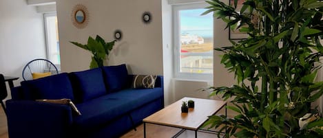 A living room with a blue sofa, a wooden coffee table, and a large green plant.