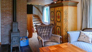 A room with a brick wall, a wooden table, a blue storage box, a tufted armchair, a patterned cabinet, and a staircase. - Cozy home in Dals-Rostock with kitchen (Dals-Rostock)