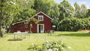 A red barn with a door and windows, surrounded by trees and grass. - Cozy home in Dals-Rostock with kitchen (Dals-Rostock)