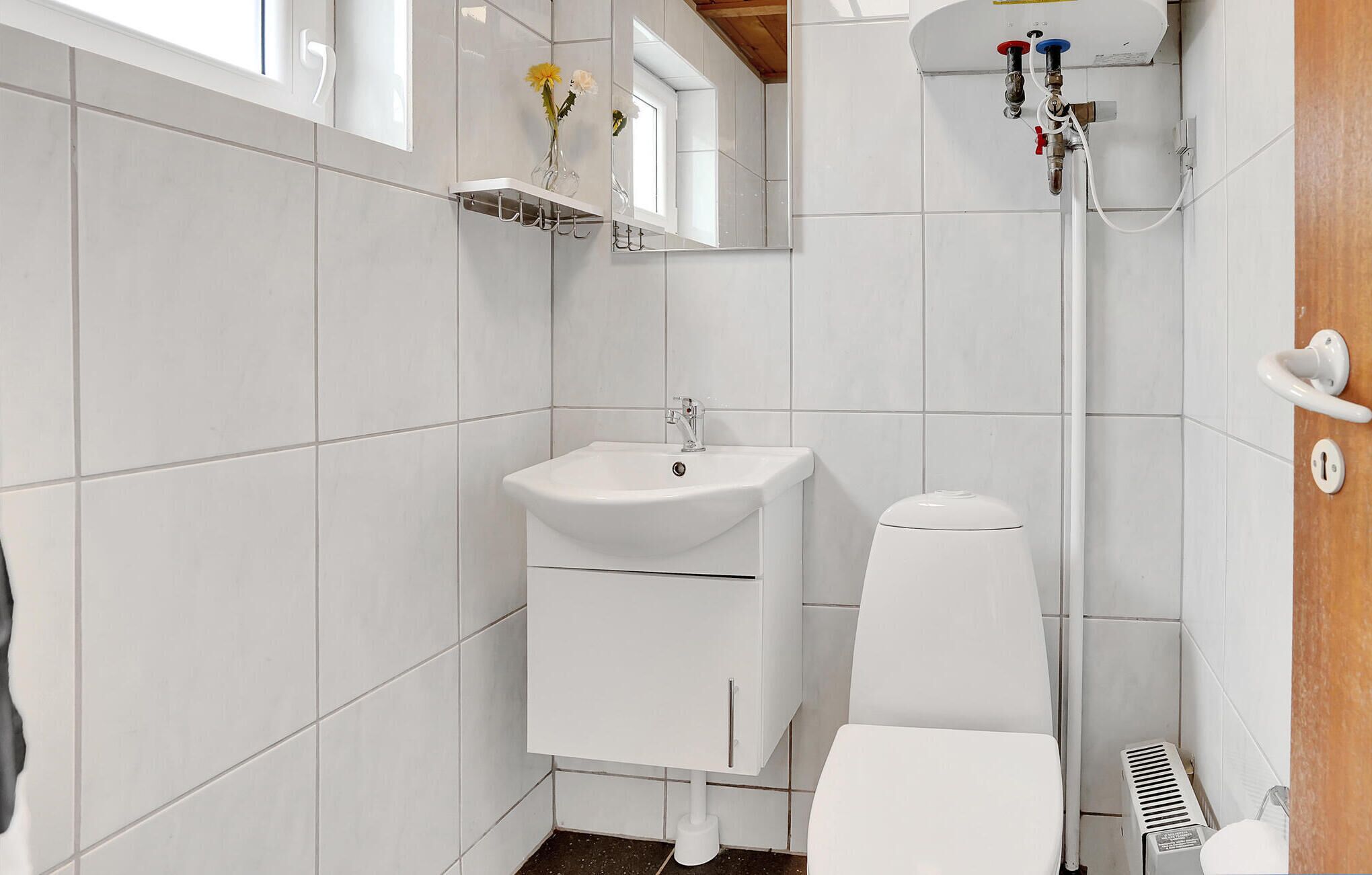 Une petite salle de bain moderne avec un lavabo, des toilettes et une douche, le tout de couleur blanche.