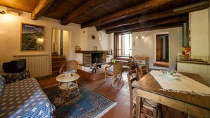 Un interior rústico con chimenea, vigas de madera y un comedor con mesa y sillas.