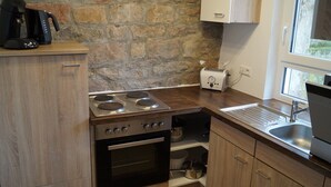 A kitchen with a gas stove, oven, and a coffee maker on the counter. - Vacation home "Lisbeth" (Edesheim)