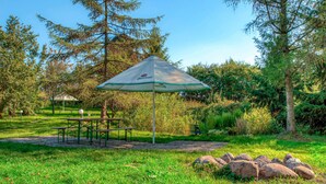 A picnic area with a table and benches, surrounded by trees and rocks.