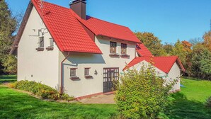 A two-story house with a red roof, a chimney, and a small garden.