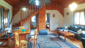 A wooden interior with a staircase, a dining area, a sofa, and a coffee table.