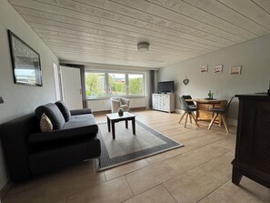 Un salon comprenant un canapé, une table basse, un téléviseur et un coin repas avec des chaises et une table.