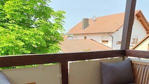 Ein Balkon mit Holzmöbeln, darunter eine Couch und Stühle, sowie ein kleiner Tisch.