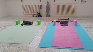 Ein Zimmer mit zwei Trainingsmatten, einem Hantelständer und einer Statue.