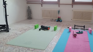 Ein Zimmer mit Trainingsgeräten, einer Statue, Heizkörpern und einer Tür.