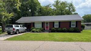 A single-story brick house with a red door and a grey roof.
