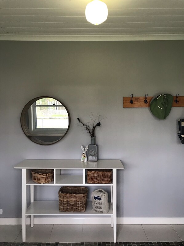 A white console table with wicker baskets and a decorative item.