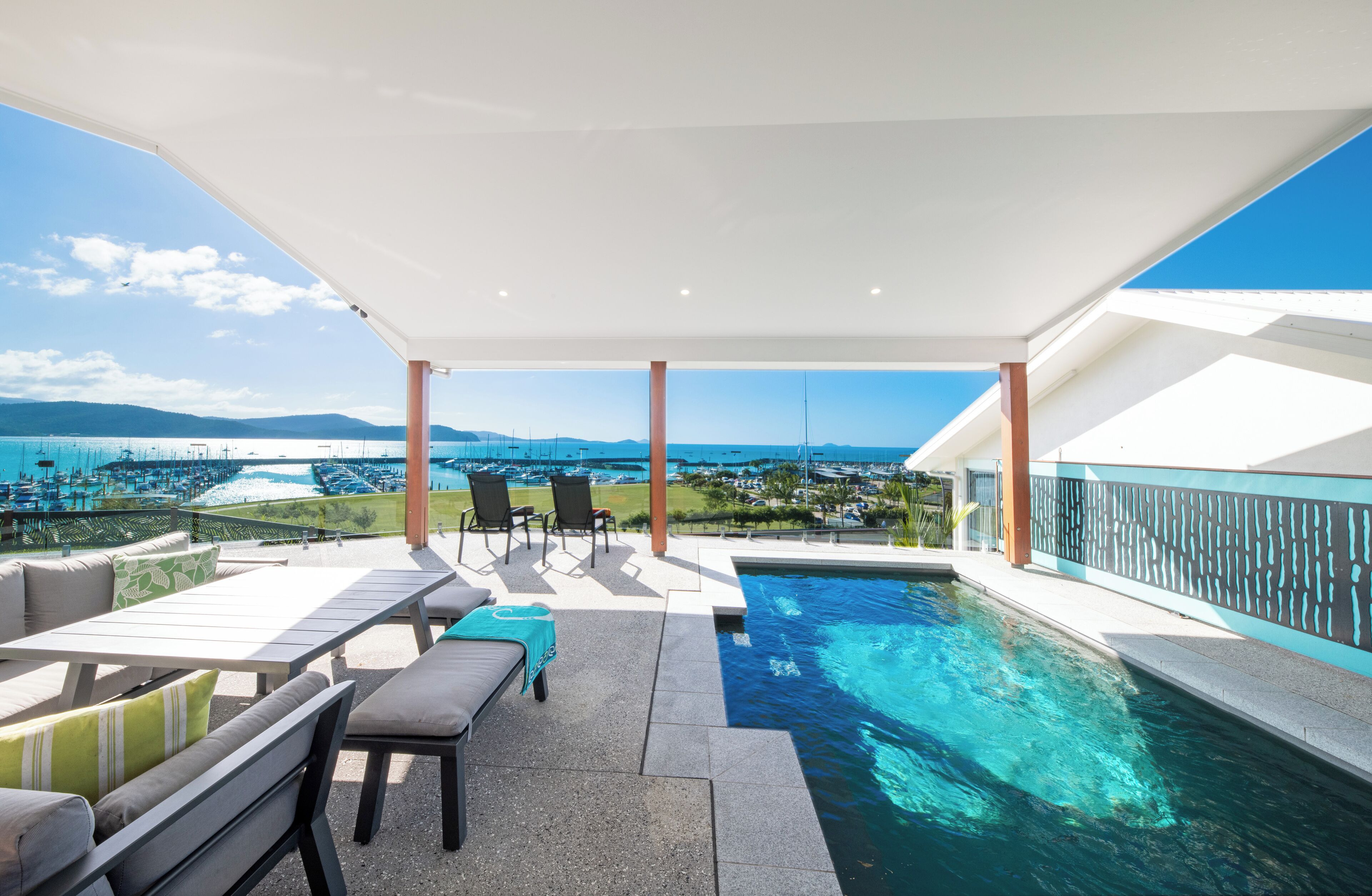 Un espace piscine sur le toit avec vue sur la mer et les montagnes, des sièges extérieurs et un patio couvert.