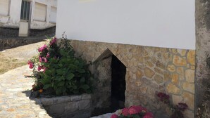 Un edificio bianco con base in pietra e tetto a tegole.