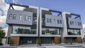 Un edificio moderno de varios pisos con techo plano, ventanas grandes y acceso a un garaje.