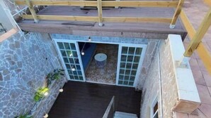 A multi-level outdoor space with a wooden deck, stone walls, and a staircase leading to a lower level. - House above the sea. Impressive. (La Puente)
