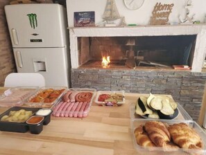 A kitchen area with a stone fireplace, a refrigerator, and various food items on the counter. - House above the sea. Impressive. (La Puente)