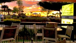 An outdoor seating area with wicker chairs and a view of a sunset.