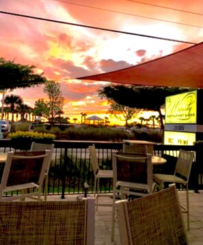 An outdoor seating area with wicker chairs and a view of a sunset.