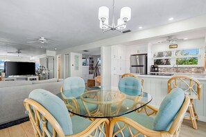 A modern kitchen with a stainless steel refrigerator, a coffee maker, and a window with blinds.