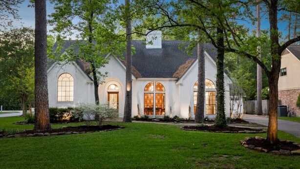A two-story house with a symmetrical facade, large arched windows, and a well-maintained lawn. - Unique Mid Century Modern in The Woodlands (Spring)