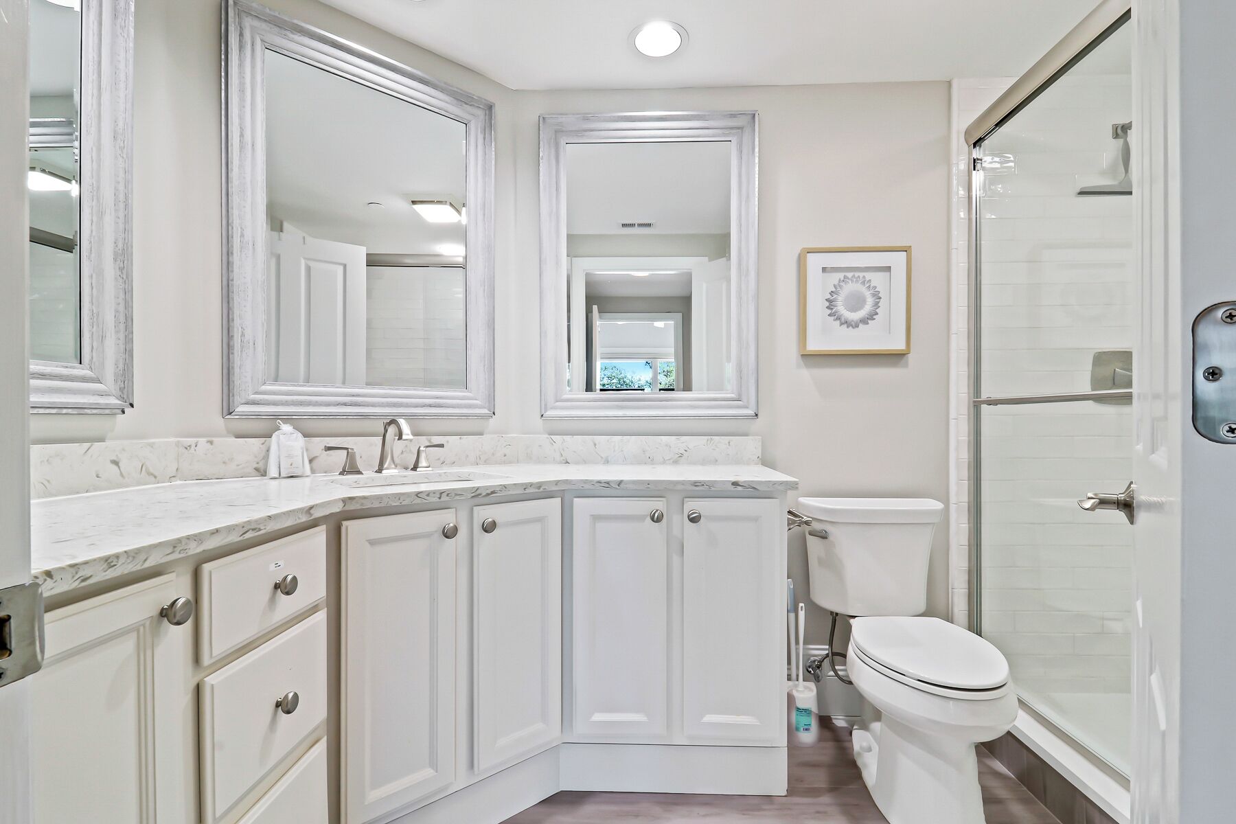 A bathroom with a white vanity, a toilet, and a shower area.