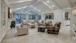 A spacious living area with a high ceiling, large windows, and a view of the outdoors. - 7 Bald Eagle-3 Row Ocean (75 yards) to the Beach &  40 ft x 10 ft Pool (Hilton Head Island)