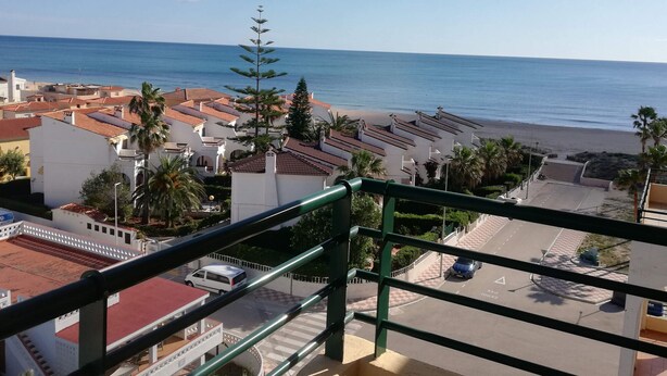 A coastal view from a balcony with a railing, overlooking a beach and a town with red-roofed buildings and palm trees. - El pilar 6º Solo familias! (Xeraco Playa)