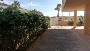 A parking area with a stop sign, a covered walkway, and a row of palm trees. - El pilar 6º Solo familias! (Xeraco Playa)