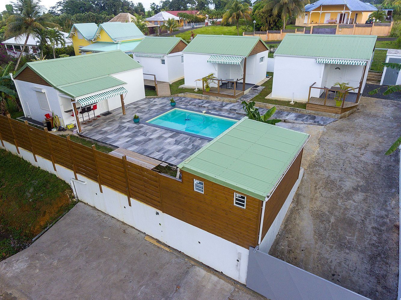 A residential area with multiple houses, each featuring a green roof and a small pool.