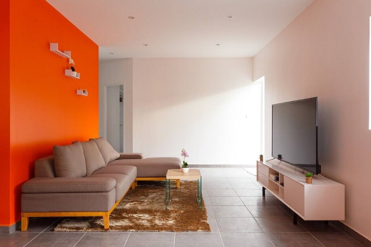 A modern living room with a sectional sofa, a flat-screen TV, and a small coffee table.