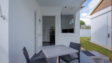A patio with a table and chairs, a window, and a door leading to an interior space.