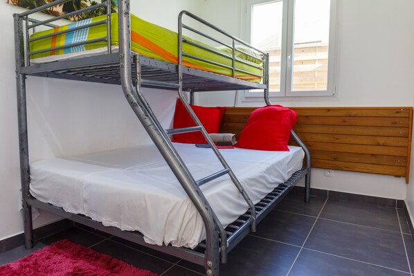 A bunk bed with a white mattress and a colorful blanket. - KAZ A BIBI (Sainte-Rose)