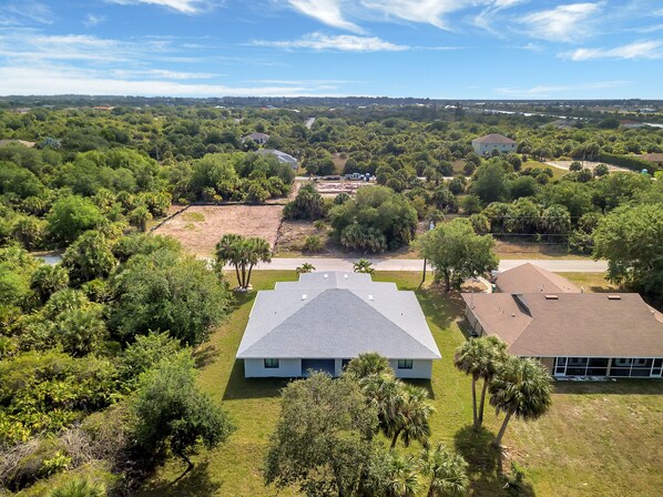 Un barrio residencial con una casa grande de techo plano y un pequeño garaje adosado.