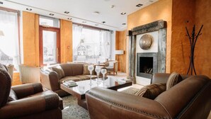 Ein modernes Wohnzimmer mit Ledersofas, einem Glastisch und einem Kamin.
